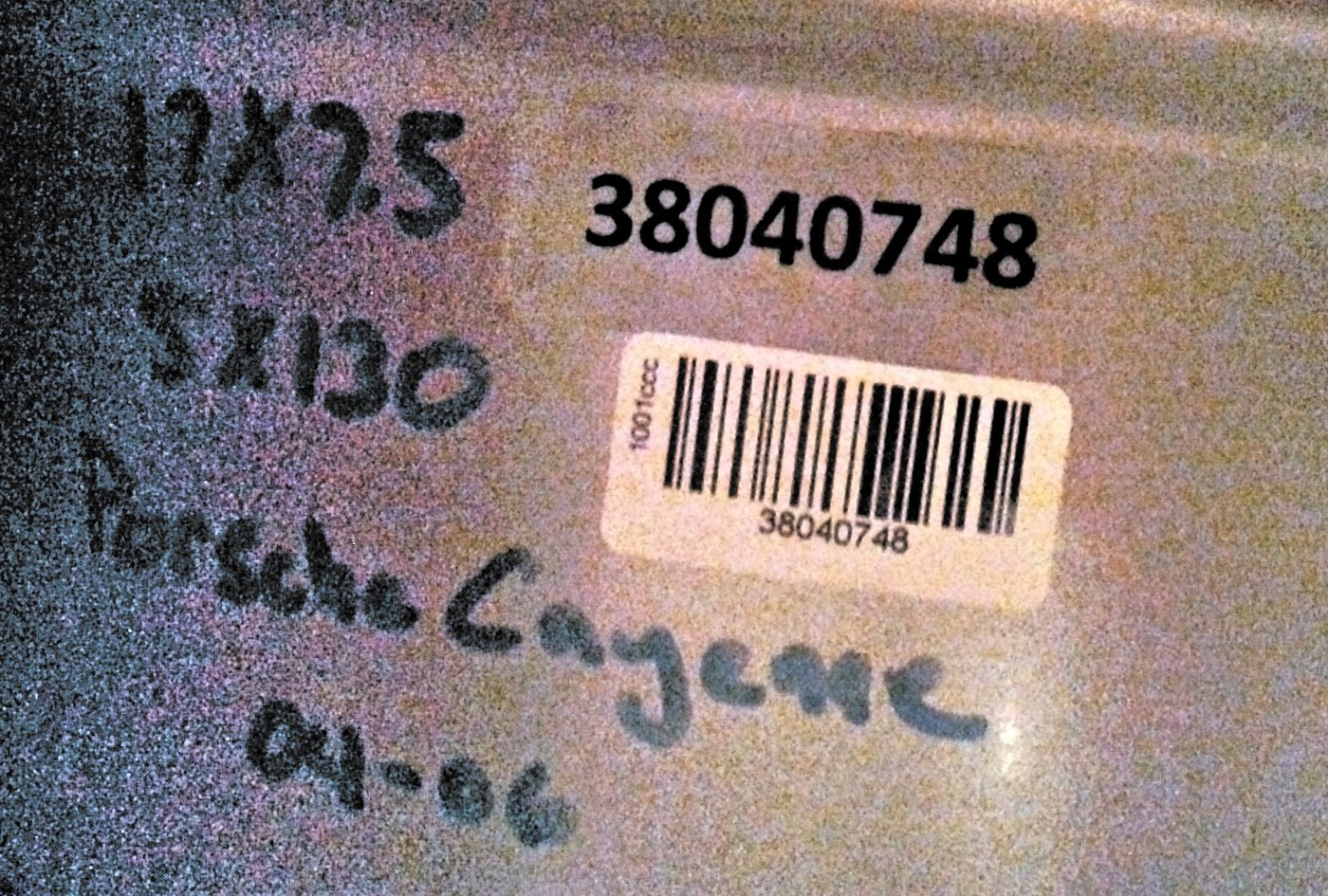 A cardboard wheel box. A clear label carries the printed item number 38040748. A smaller white barcode label beside it carries the same number, with the roll code 1001ccc down its edge. Vehicle specs are written beside both in black marker